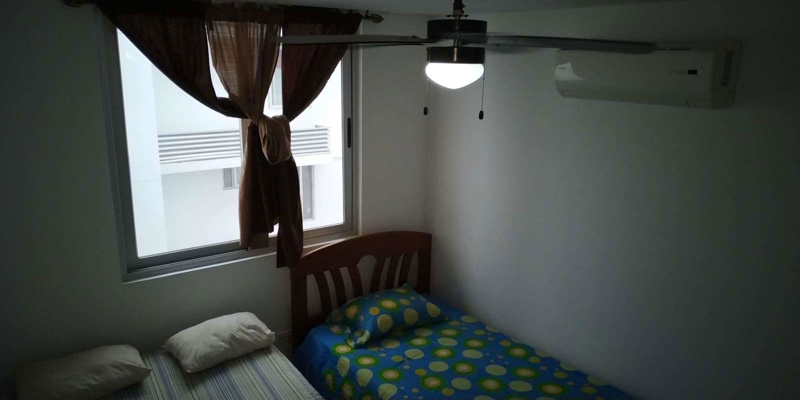 Bedroom with bed, AC, window, brown curtains PH Transistmica Panama