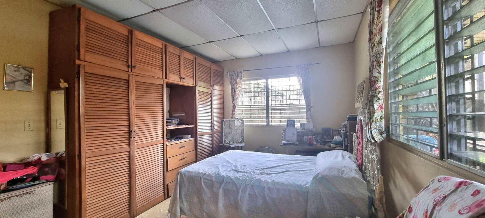 Bedroom in residential house featuring built-in closet, security bars and window Panama
