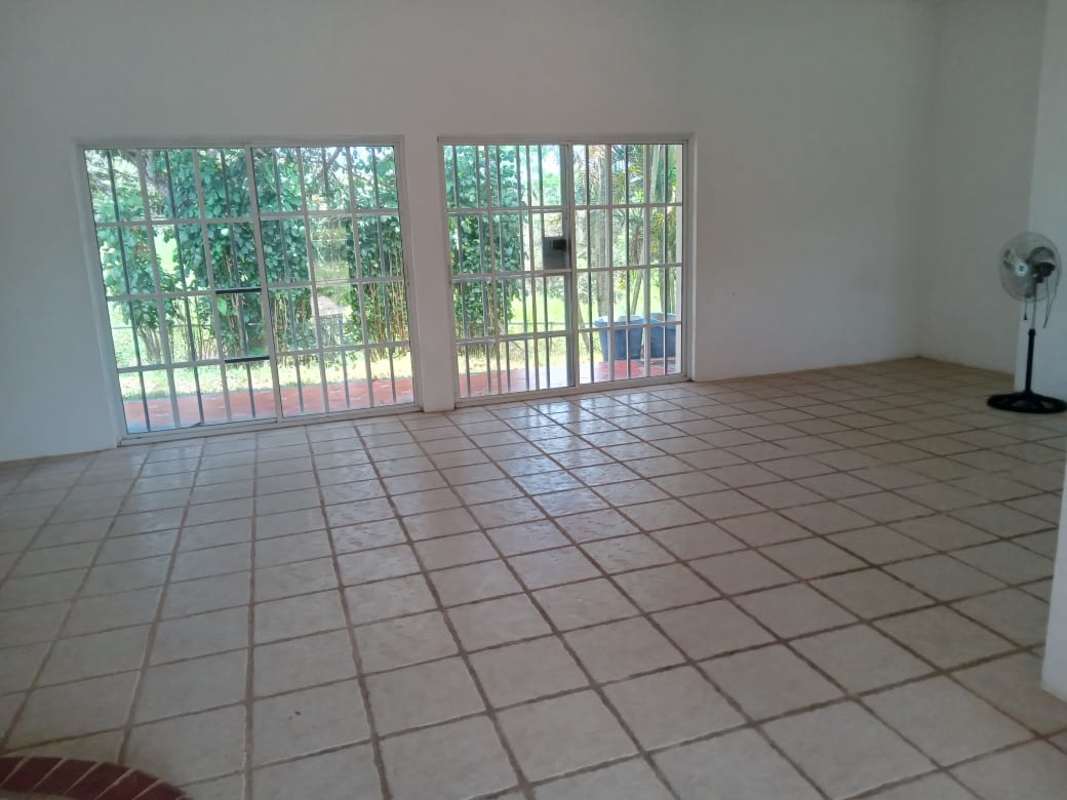 Minimalist living room with large tiled floors, windows with security bars at Cerro Azul Panama