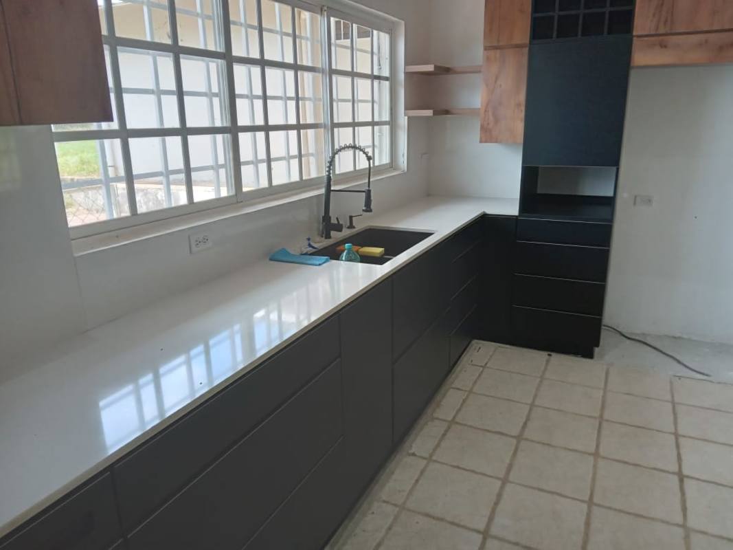 Kitchen with black and wood cabinetry, large windows, white countertop Cerro Azul Panama