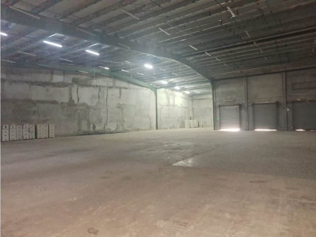 Empty warehouse with exposed concrete walls, high metal ceilings and concrete floors