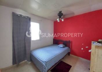 Bedroom with red accent wall, ceiling fan, and window at Urbanización El Edén, Arraiján