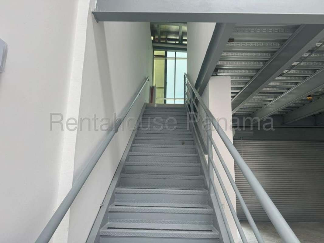 Metal industrial staircase inside warehouse connecting ground floor with mezzanine office level in Panama Viejo complex