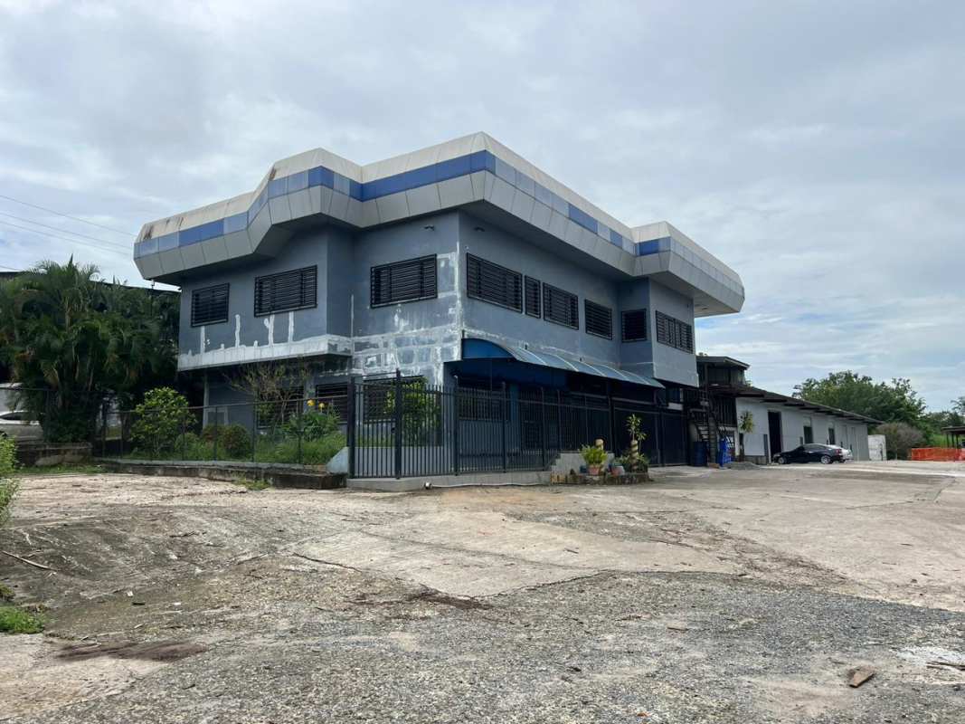 Blue two-story commercial building with metal security gate and outdoor staircase in Panama