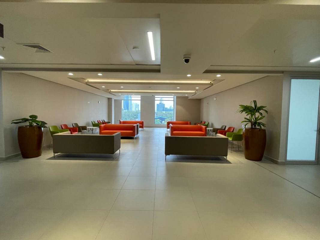 Lobby with multiple colorful chairs, sofas, plants near large windows in Costa del Este office building