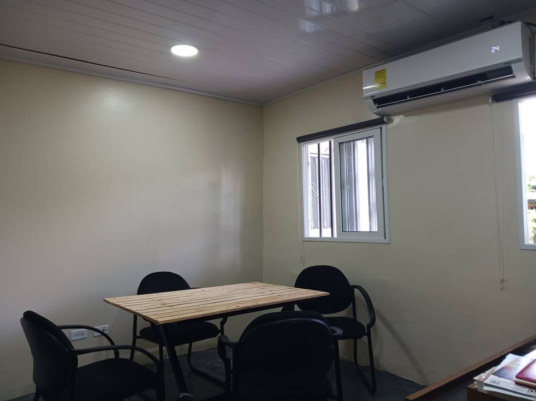 Small conference or meeting room with wooden table and wall AC unit in Betania office.