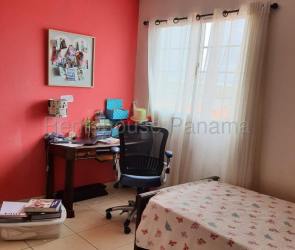 Bedroom with red accent wall, natural light, and desk space in duplex house La Chorrera