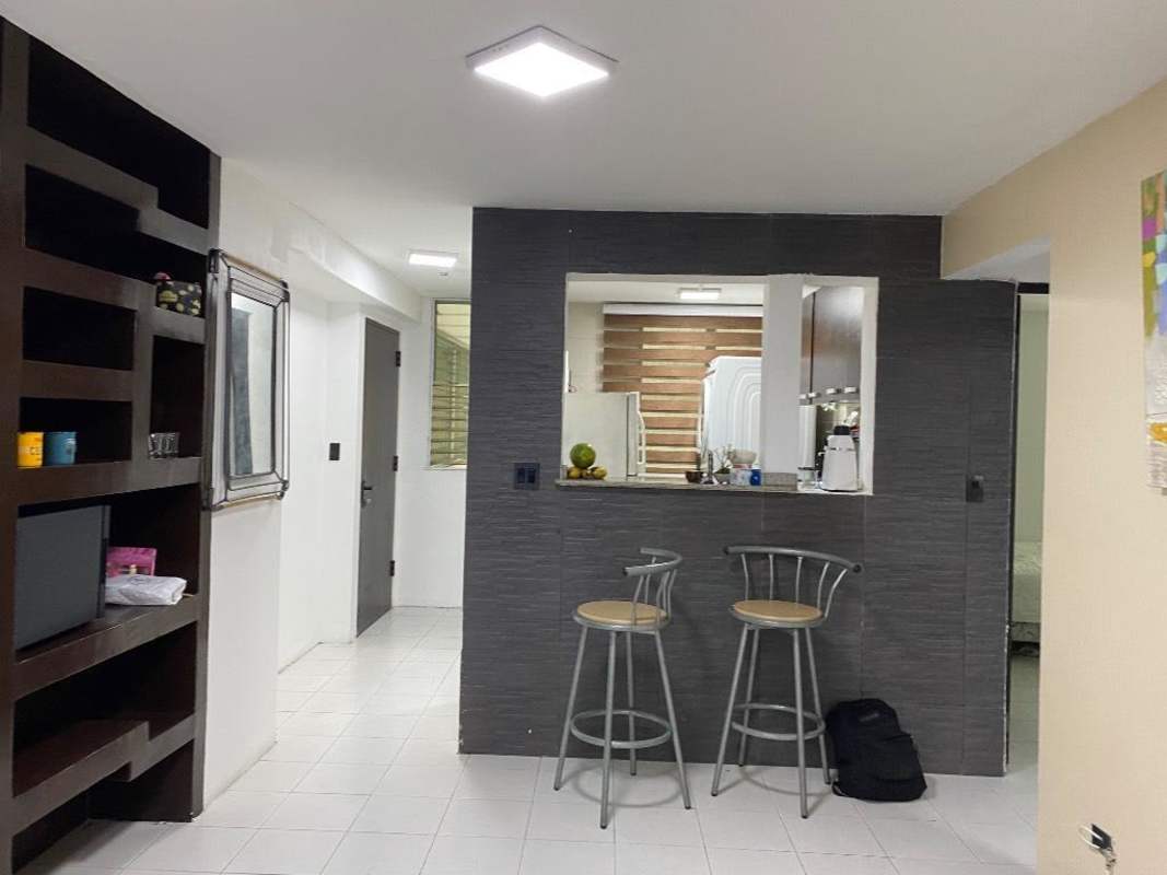 Modern open-plan living area with built-in shelving and breakfast bar in Edison Park apartment Panama City