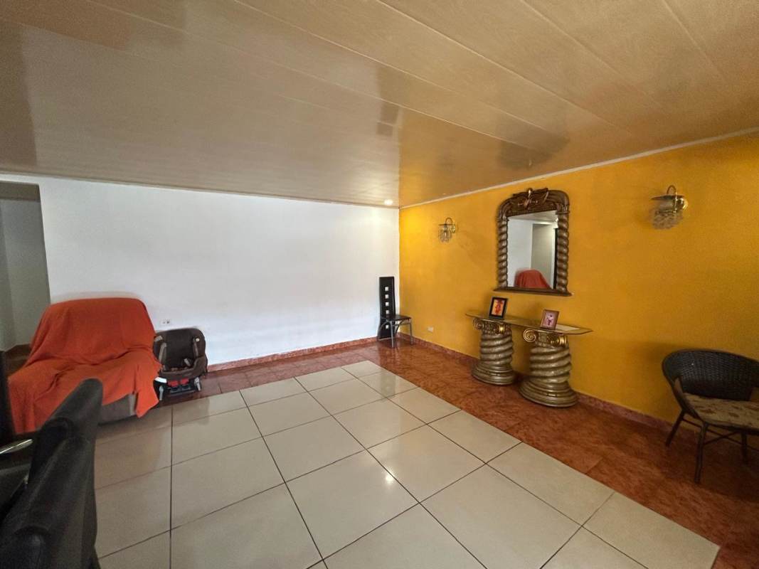 Living room with yellow accent wall, decorative mirror, and ceramic tile floors at Don Bosco house