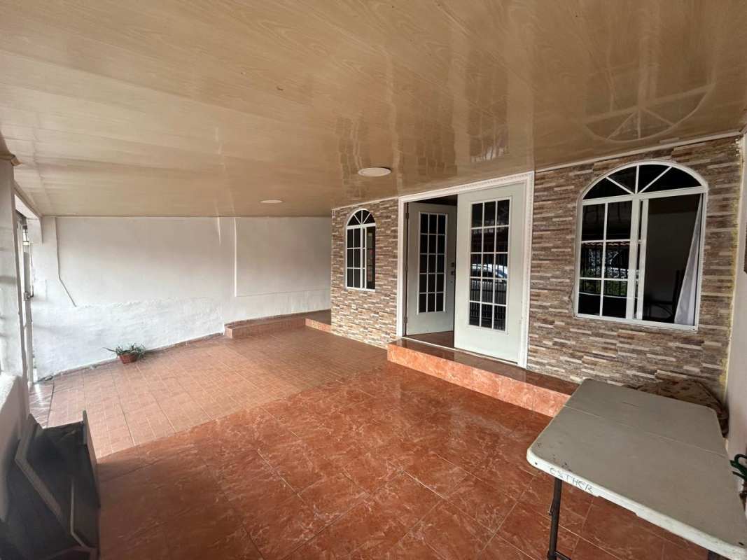 Covered tiled patio with stone wall and double doors at Don Bosco Urbanización Los Robles house