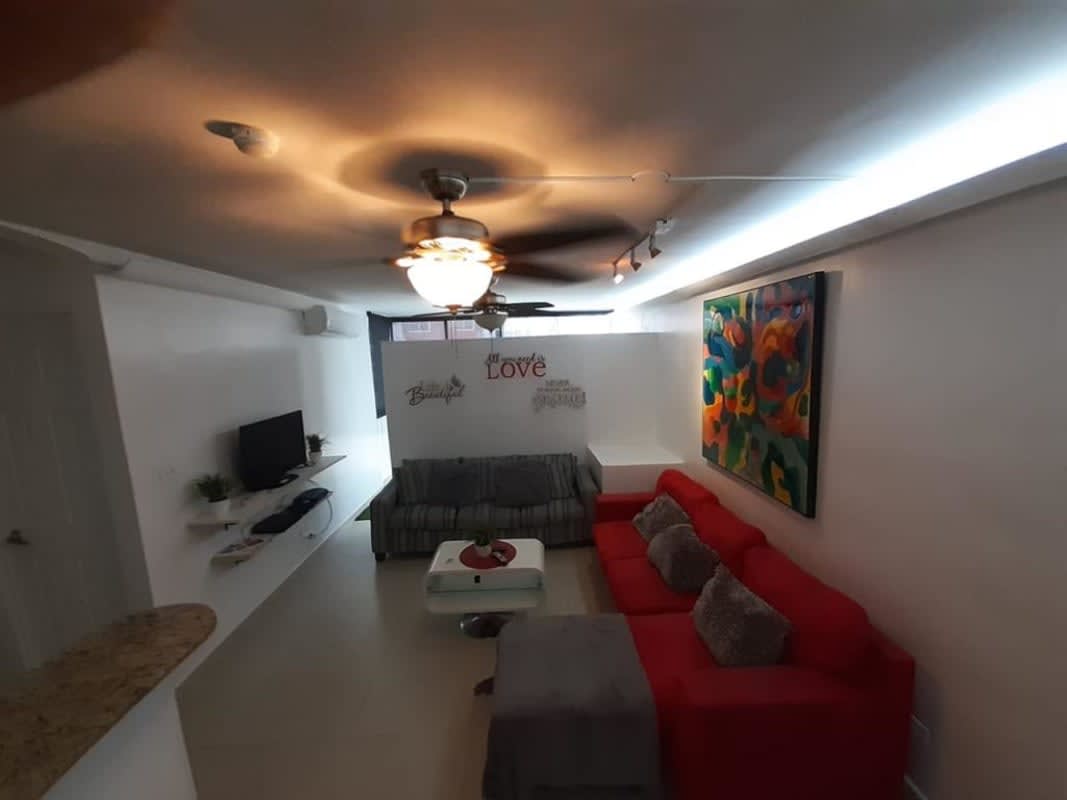Living space with red sofa granite bar PH Condado Gardens Condado del Rey Panama