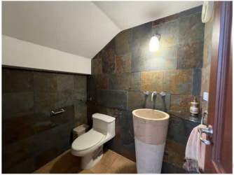Modern bathroom with stone tiles, pedestal sink, contemporary fixtures at luxury villa Panama