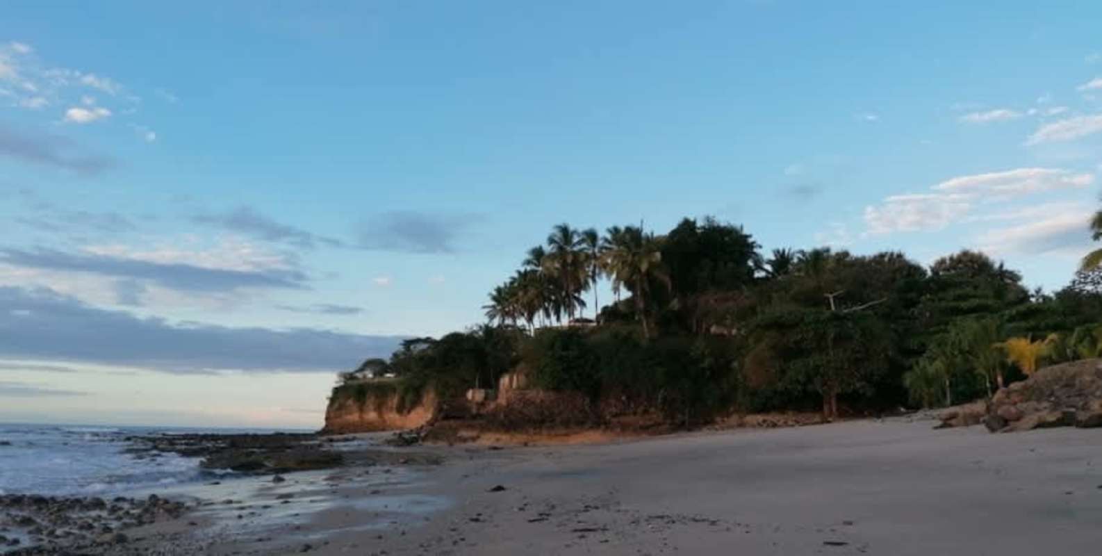 Light-filled living area with glass doors opening to balcony overlooking the Pacific Ocean