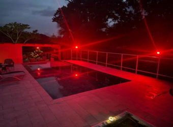 Night-lit outdoor pool terrace with lounge chairs in Panama lake estate property Capira