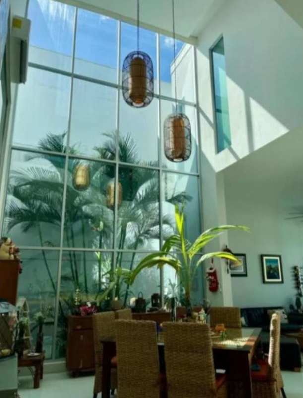Double height dining area with floor to ceiling glass windows modern pendant lights tropical decor Panama