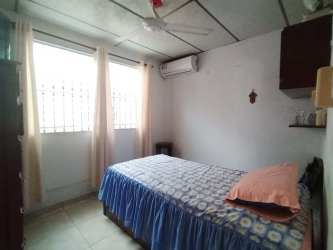 Bedroom with AC unit, ceiling fan, window bars in house in Panama City