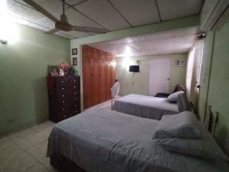 Bedroom with two beds, ceiling fan, large wardrobe in Santa Clara house Panama