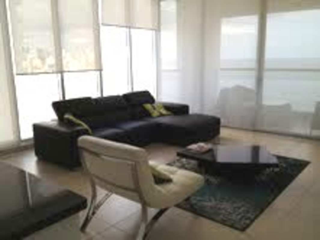 Spacious living room with floor-to-ceiling windows, black sectional sofa, panoramic ocean skyline views at BICSA Tower