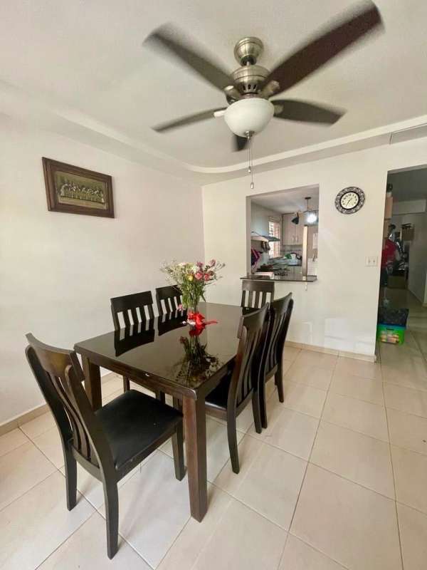 Dining area with six-seat glass table, ceiling fan and wall art in family house Villa Lucre Panama City