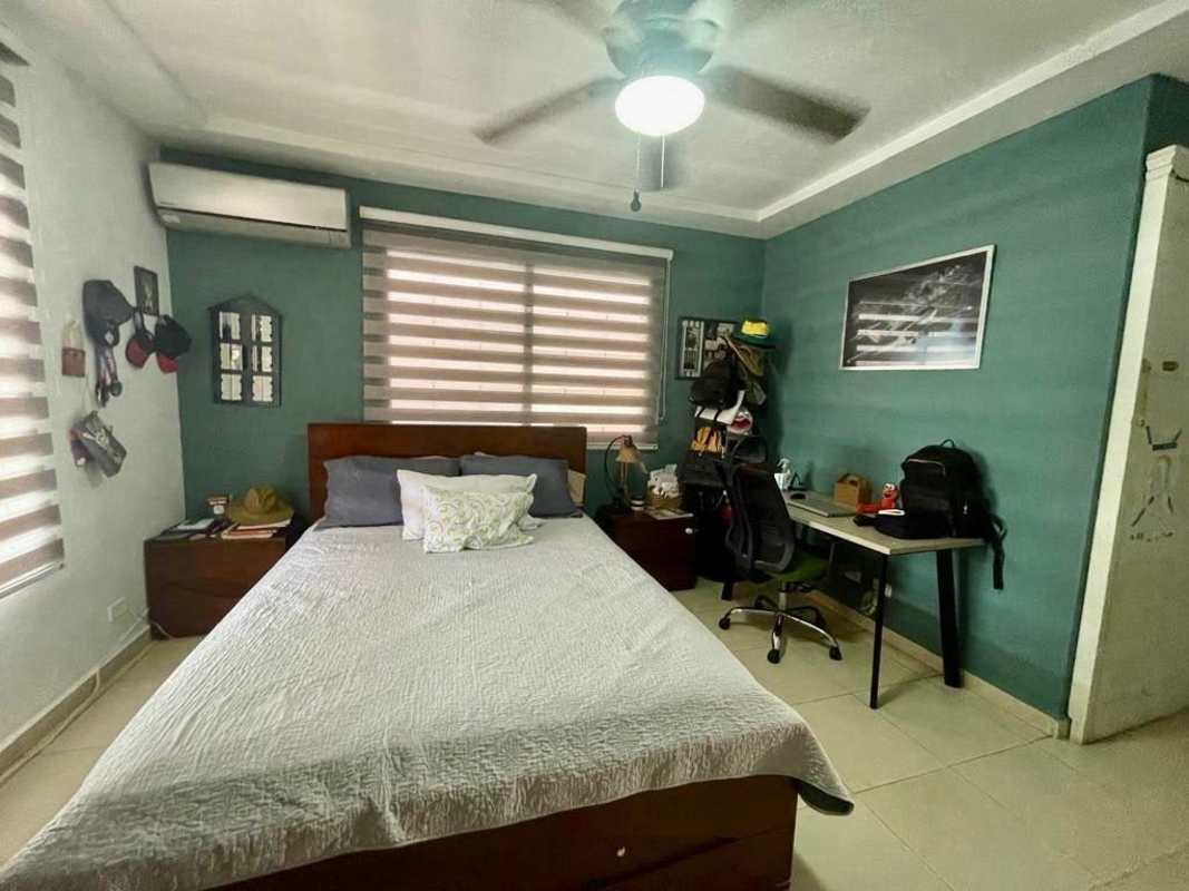 Master bedroom with teal accent wall, split AC, ceiling fan, bed with pillows, work desk in Villa Lucre Panama home