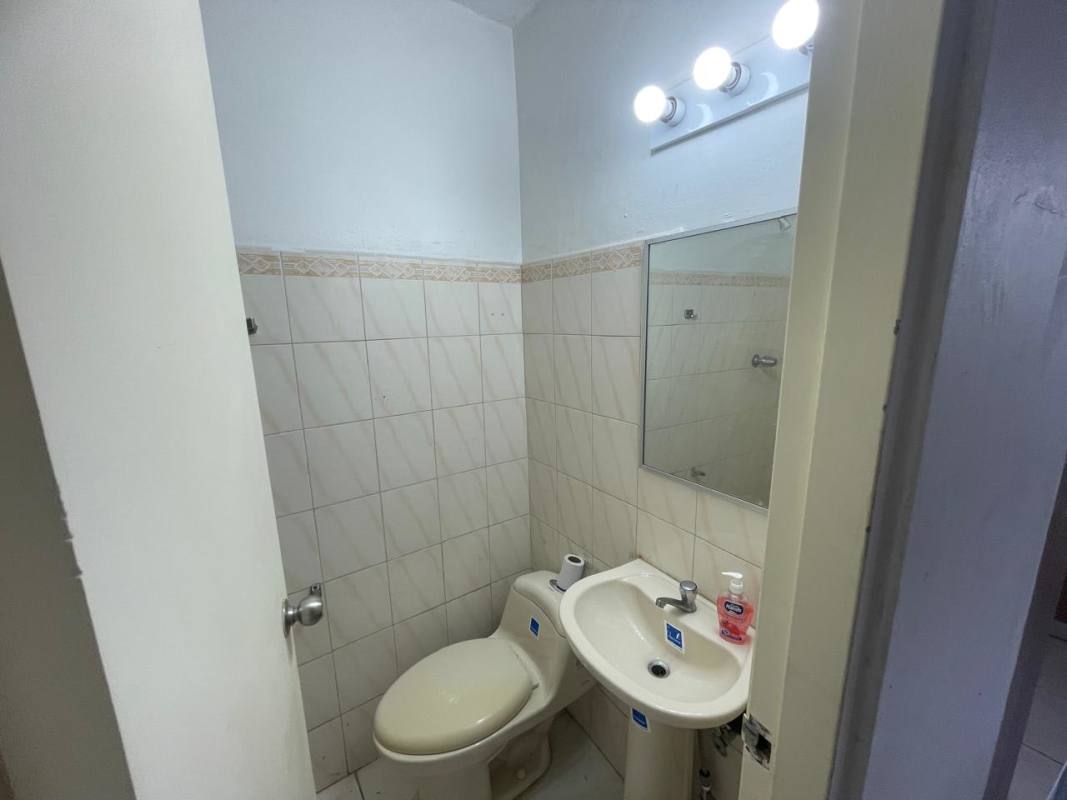 Compact bathroom with pedestal sink, toilet, beige tiles in PH Beverly Hills Betania Panama apartment rental