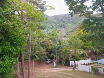 Spacious open living room with tile flooring, ceiling beams, staircase access in mountain house Capira Panama