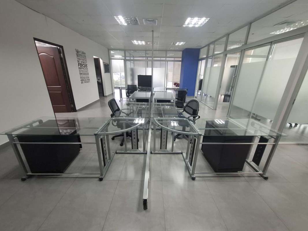 Modern furnished open workspace area with glass desks and tiled floors at PH Office One Obarrio Panama