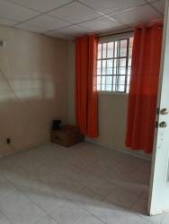 Empty tiled room with security bars and orange curtains in Villas de la Alameda residential Arraiján Panama