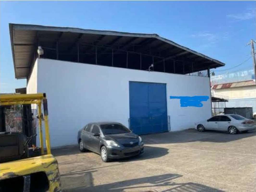 Facade of industrial warehouse with double blue metal doors, parking area, Villa Rica Panama City