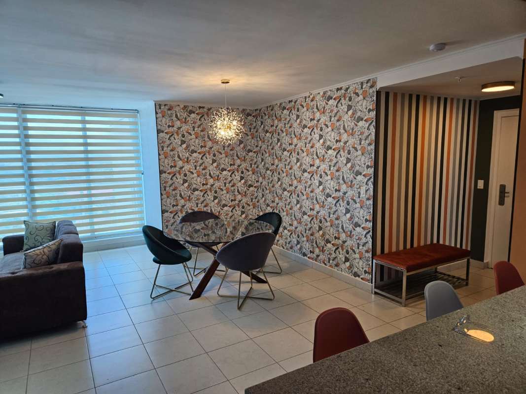 Furnished living and dining area with balcony and large window at PH Miró Panama City