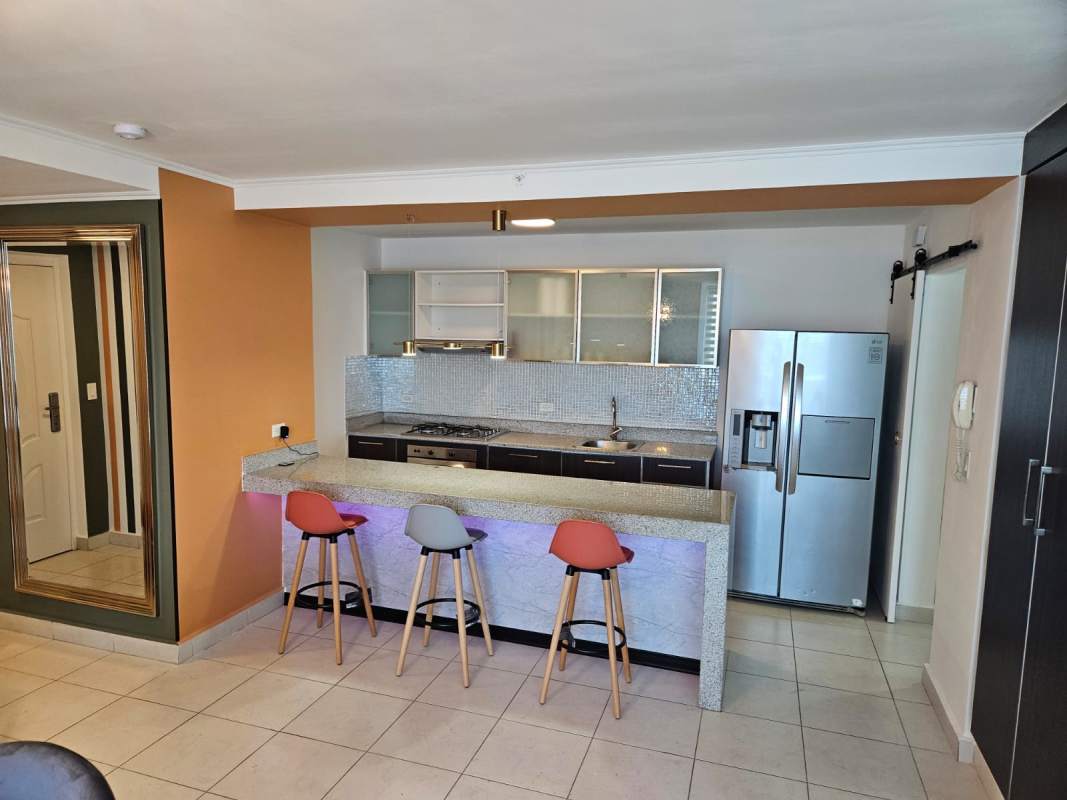 Open kitchen with granite island, mosaic backsplash and appliances at PH Miró Panama