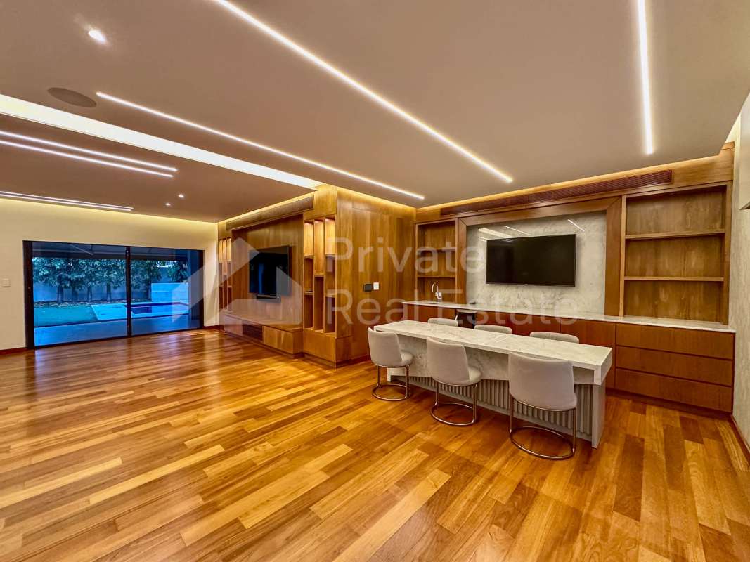 Luxurious living area with hardwood floors, built-in bar, sliding doors to pool in PH Antigua Costa del Este Panama