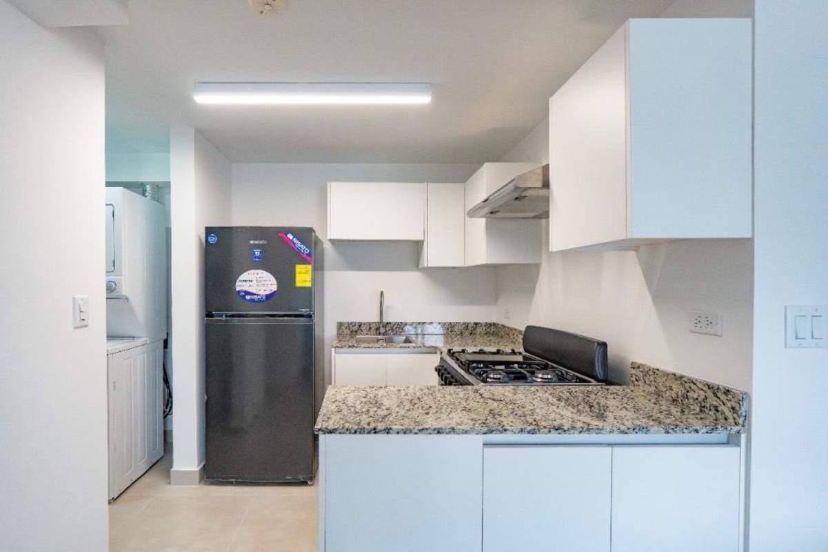 Compact kitchen with granite countertop, stove, refrigerator, washer dryer in Panama Viejo Residences