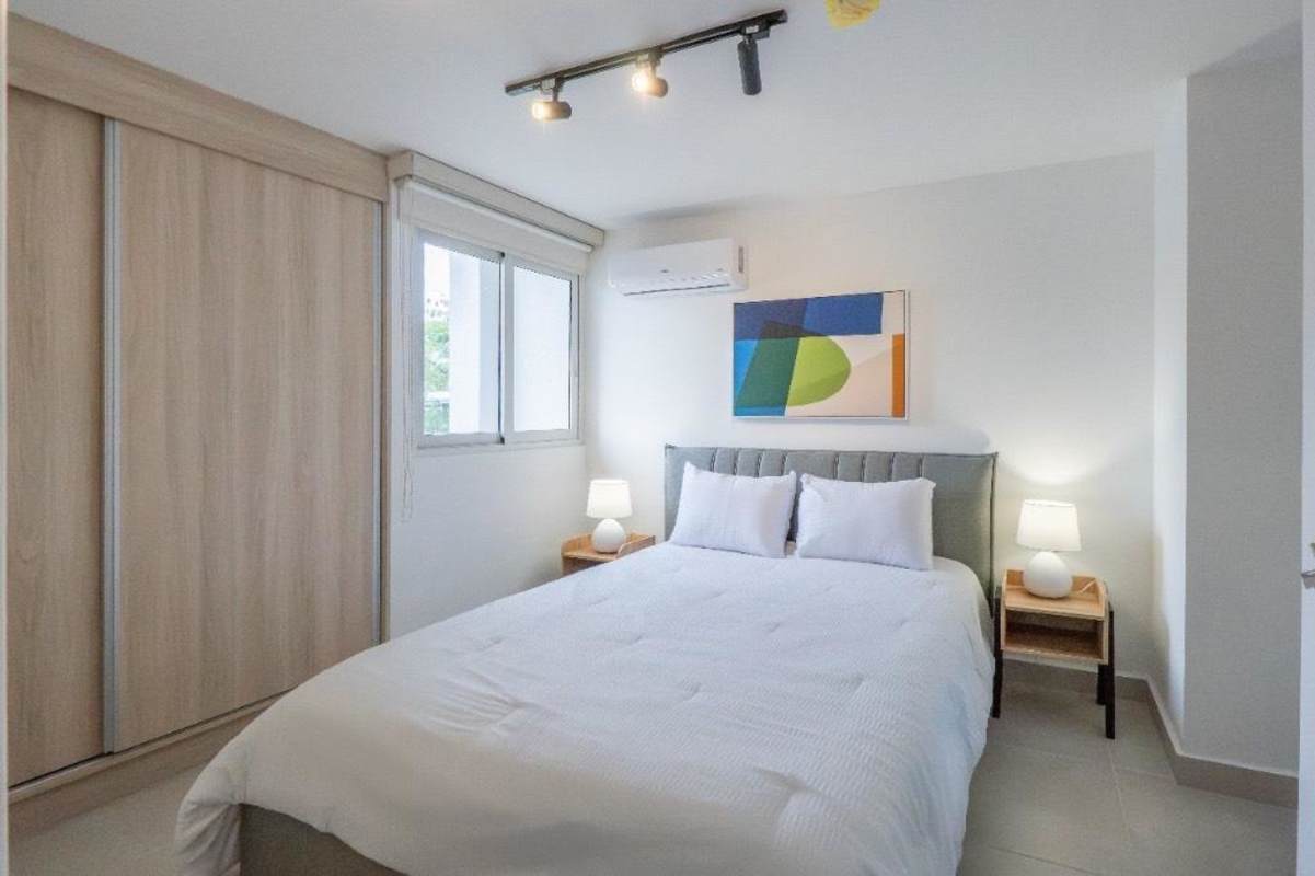 Furnished bedroom with ensuite bathroom, AC and modern decor at Panama Viejo Residences Panama City
