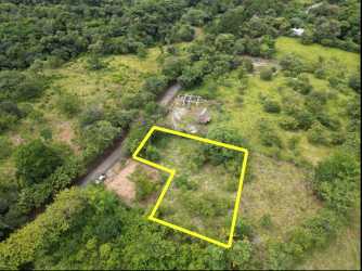 Open plot with fence, mature trees and dry grass along entrance road in Santa Catalina Panama