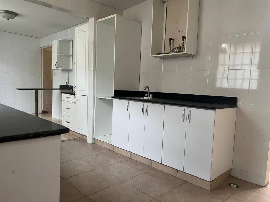 Spacious kitchen with black countertops, white cabinetry and tile backsplash Panama