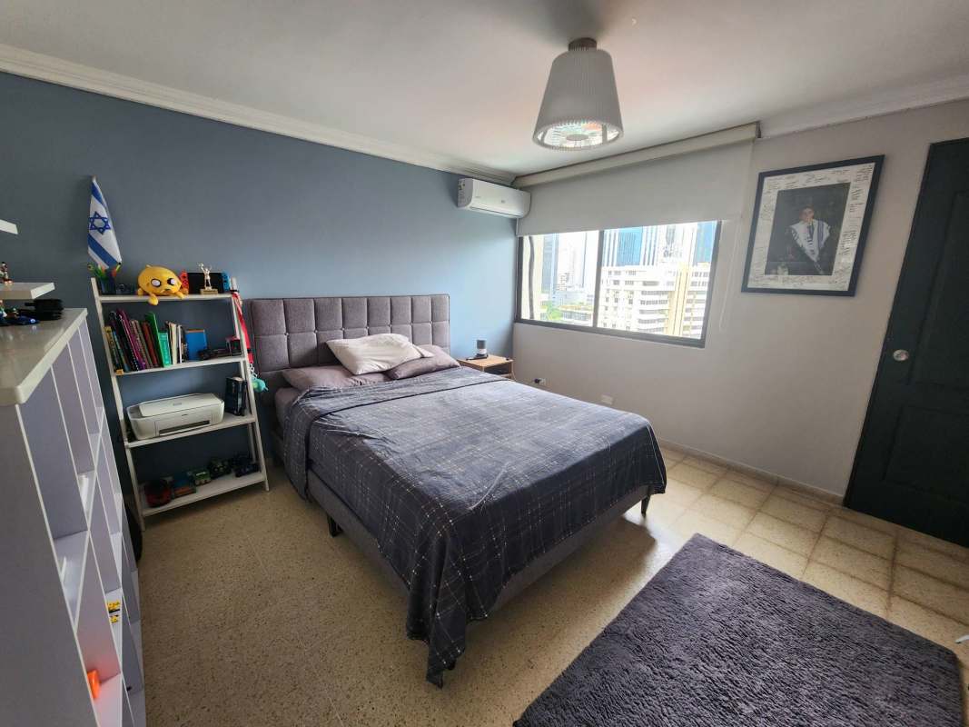 Modern bedroom with large window, city skyline views, split AC and neutral colors at PH Torre Marbella Panama City