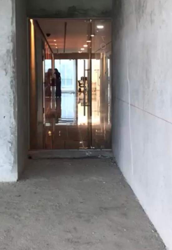 Entrance hallway of commercial shell space with glass doors and exposed concrete