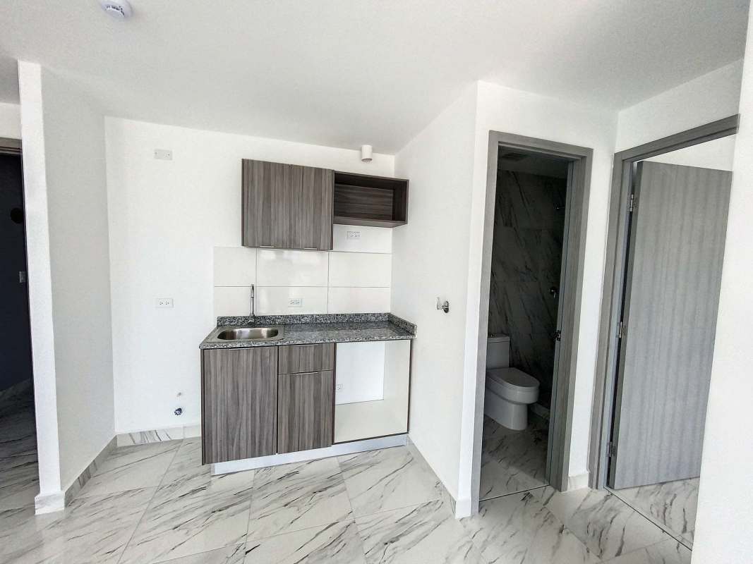 Kitchenette with granite countertop and adjacent bathroom in PH Botánico