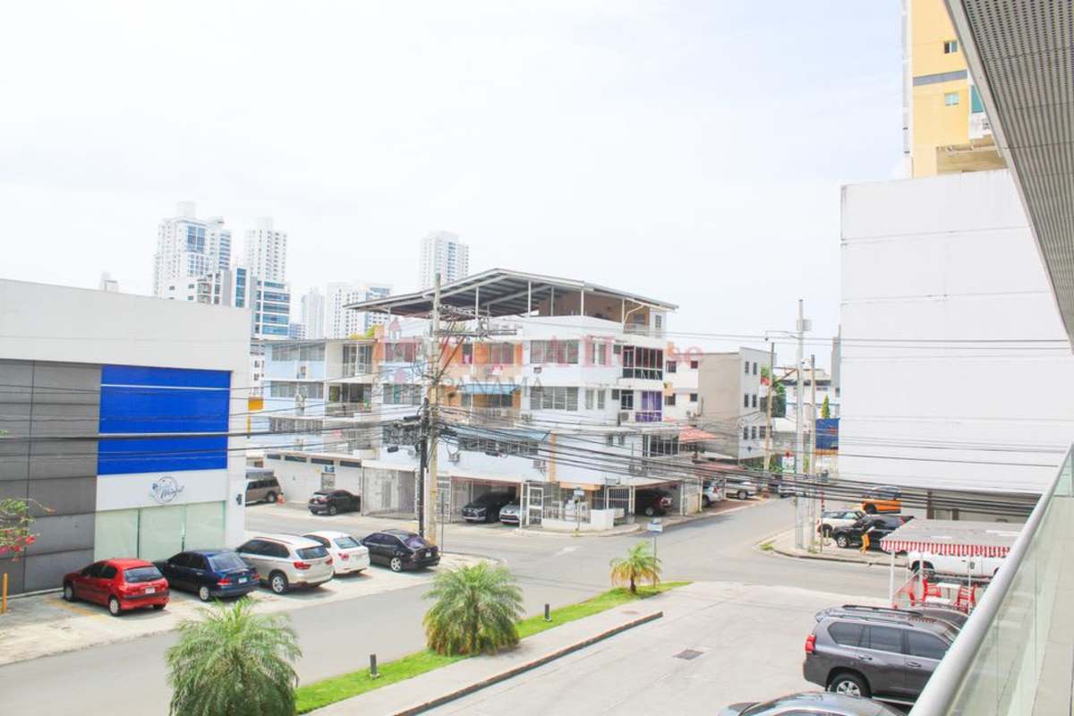 Street view of commercial complex with multiple storefronts and parking at San Francisco Plaza