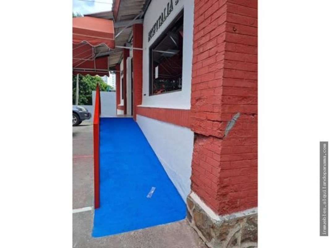 Exterior photo of commercial building side showing blue wheelchair ramp, windows and brick wall on Calle 50 Panama City