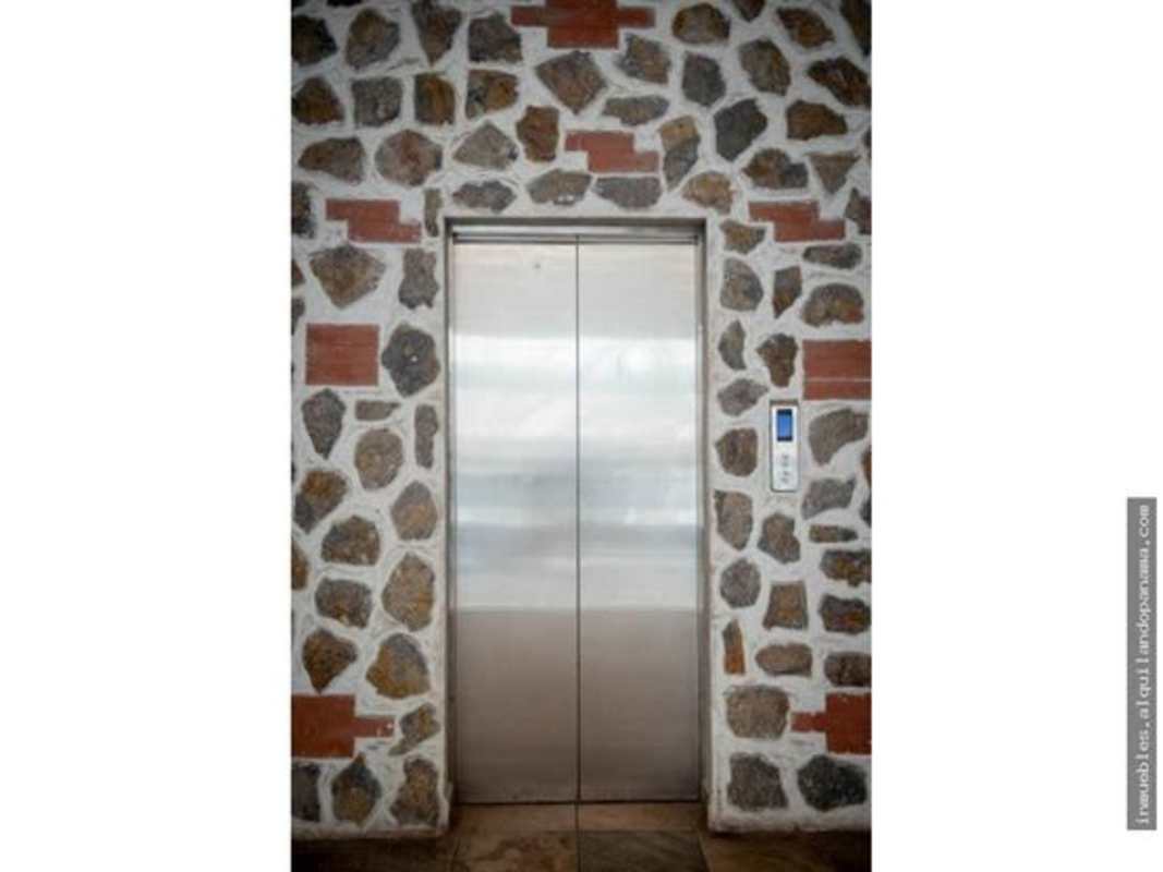 Rustic stone wall lobby with modern elevators at Plaza Bella Vista Panama