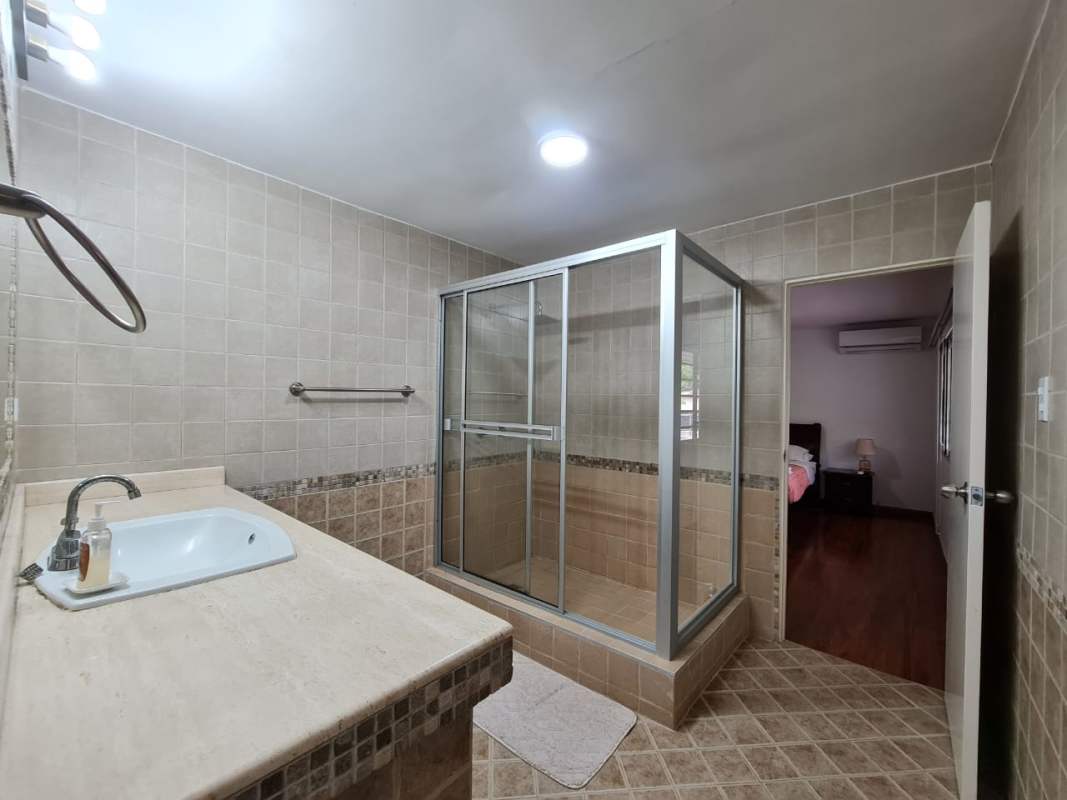 Bathroom with glass shower, tile walls and built-in sink in Clayton furnished house rental