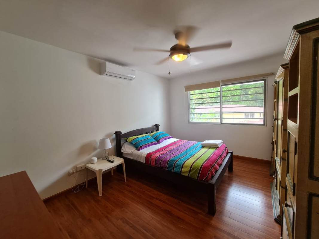Bedroom with wooden floor, large window, AC, and closet in Clayton furnished rental
