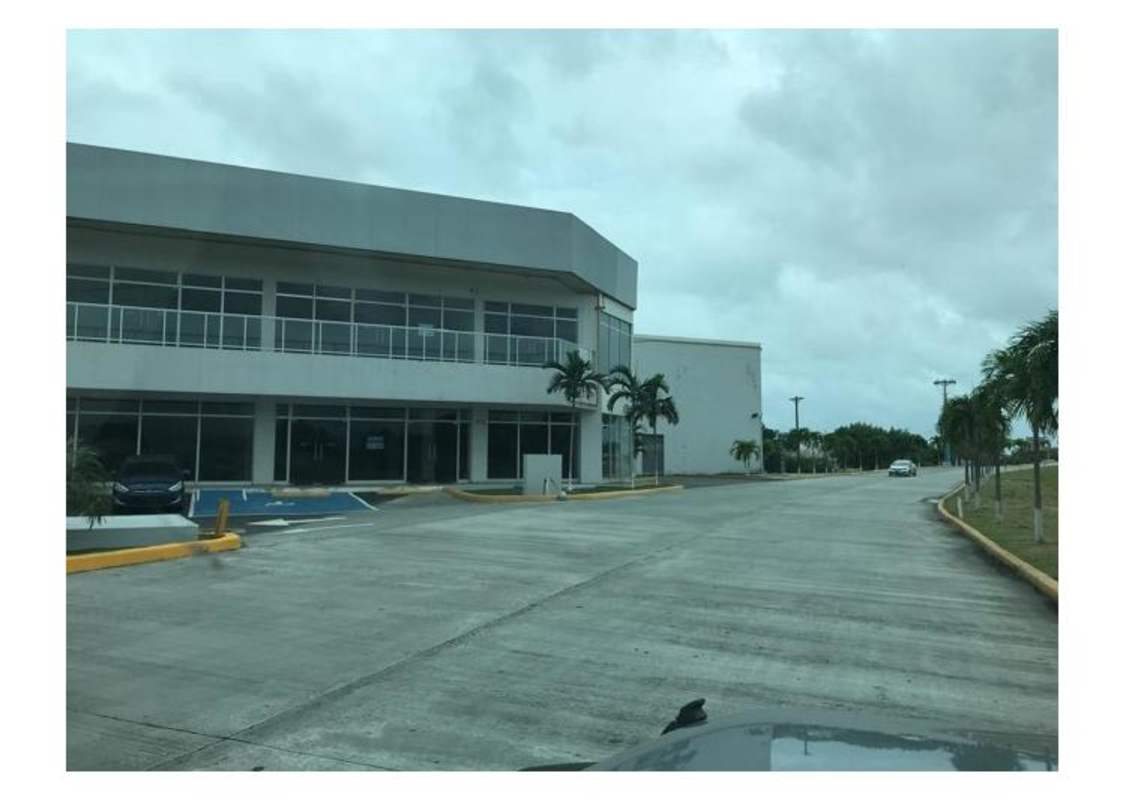 View of shopping complex exterior with upper balconies, palm trees, parking lot Costa Sur Panama