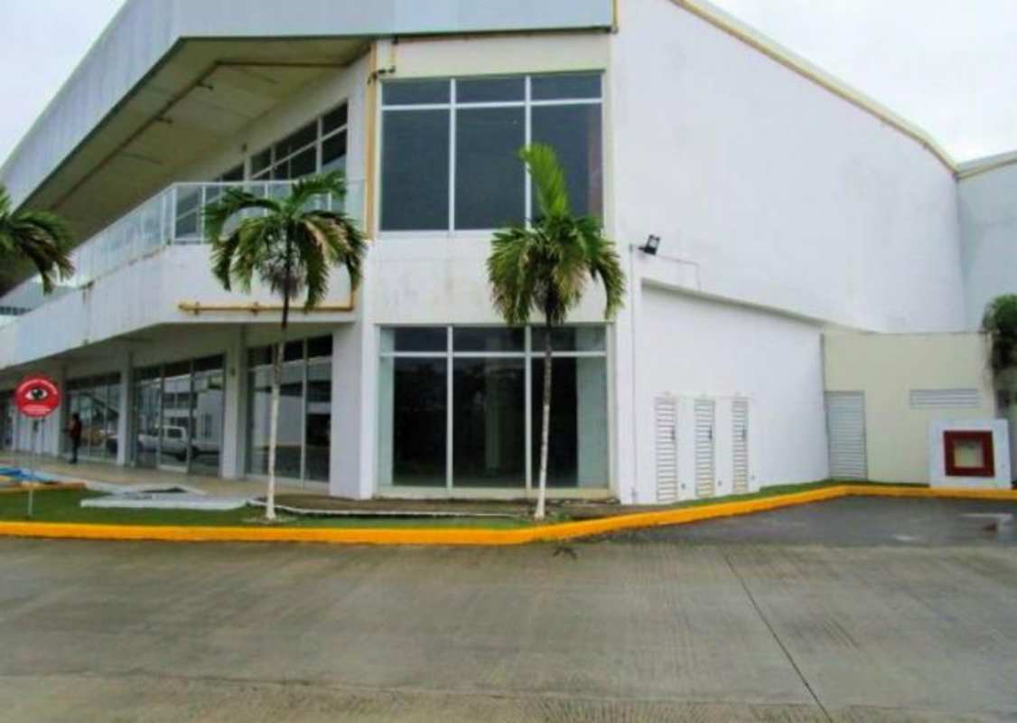 Street corner view of modern shopping center with glass façade, balcony and palm trees in Panama