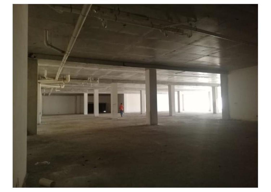 Large open unfinished gray commercial space in Panama's Costa Sur plaza with high ceiling and columns