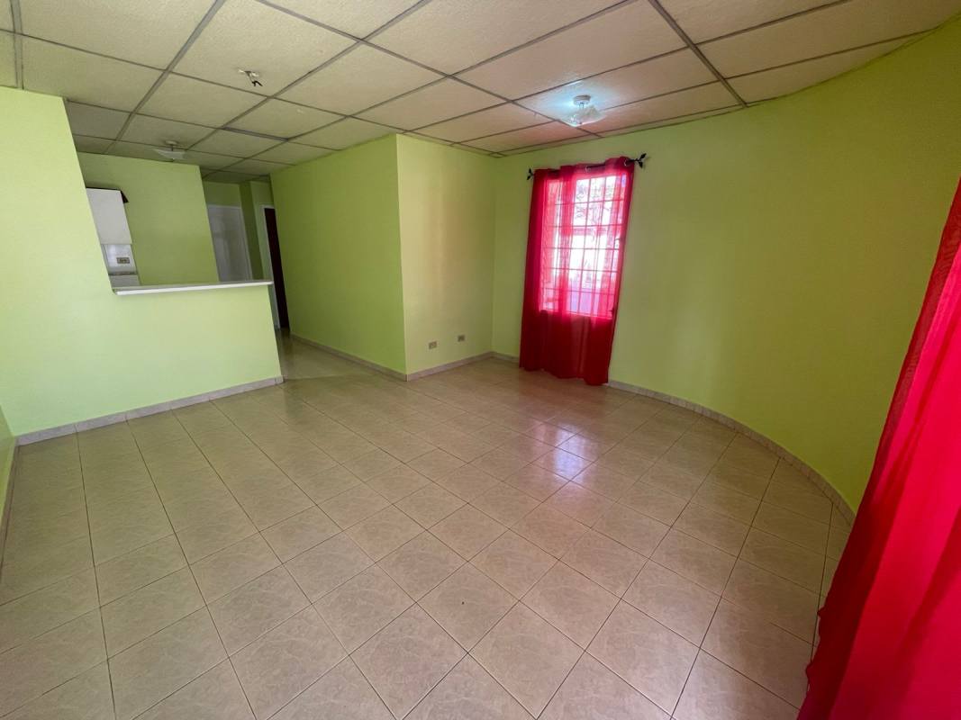 Compact kitchen with breakfast bar, light green walls and cabinets in Las Acacias house Panama City