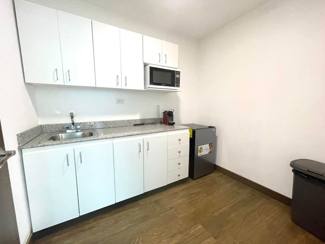 Modern kitchenette with white cabinets and appliances inside office Financial Park Tower Panama