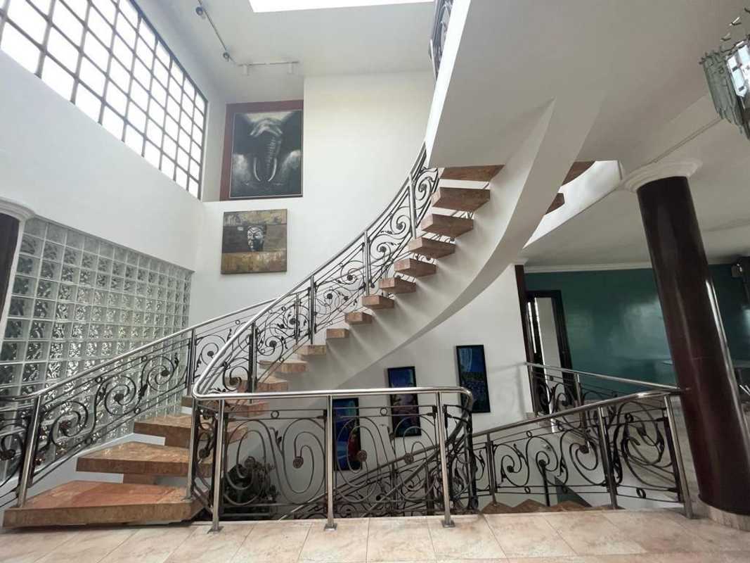 Curved staircase with marble steps, glass block wall, skylight in Dos Mares luxury home Panama